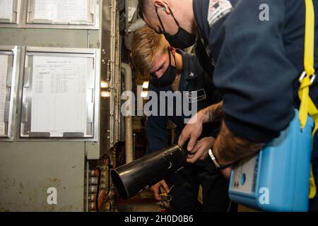 210127-N-RG587-1023 OCEANO ATLANTICO (GEN. 27, 2021) Electrician's Mate Petty Officer terza classe Zachary Nichols, a sinistra, assegnato alla nave da crociera missilistica guidata classe Ticonderoga USS Vella Gulf (CG 72), prepara un estintore a CO2 per l'uso il 27 gennaio 2021. Il Golfo di Vella è in corso nell'Oceano Atlantico e svolge le sue attività nell'ambito del gruppo Dwight D. Eisenhower Carrier Strike Group. Foto Stock