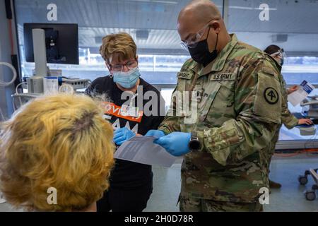 SPC dell'esercito degli Stati Uniti. Wright, 44th Infantry Brigade Combat Team, New Jersey Army National Guard, pone una domanda a un fornitore di assistenza sanitaria presso il nuovo sito di vaccinazione COVID-19 di Bergen County, aperto a East Rutherford, N.J., 29 gennaio 2021. I soldati cittadini stanno assistendo gli operatori sanitari nello screening della temperatura, immettendo informazioni assicurative, guidando gli individui attraverso le varie stazioni e monitorando le persone dopo aver ricevuto le vaccinazioni. Il New Jersey ha sei mega-siti in tutto lo stato situati in Atlantic, Bergen, Burlington, Gloucester, Middlesex, E le contee di Morris. (Ne Foto Stock
