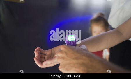 Controllare la temperatura a portata di mano. Media. La gente va ai centri commerciali e al cinema attraverso il controllo della temperatura. Termometro a infrarossi a pistola. Non contattare il Foto Stock