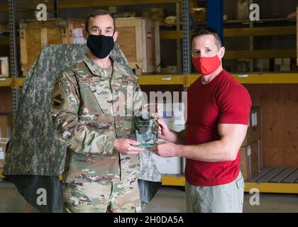 Colorado Air National Guard Lt. Col. Trevor Ibsen, 140th Logistics Readiness Squadron Commander, presenta un segno di apprezzamento a Marc Harvill, un artista della zona di Denver, durante un'illustrazione rivela alla base dell'aeronautica di Buckley, Colom., 29 gennaio 2021. Harvill ha creato l'opera per mostrare il suo apprezzamento per il 140esimo LRS. Foto Stock