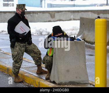 210202-N-EJ843-0087 GROTON, Conn. (Feb 02, 2020) Master-at Arms Seaman George DeAngelis assegnato alla base navale sottomarina di New London, prende copertura e mira la sua arma di addestramento durante un trapano simulato del corridore del cancello, mentre Master-at Arms 1st Class Jeremy Whittaker valuta l'evoluzione a sostegno dell'esercizio Citadel Shield-Solid Curtain 2021 (CS-SC21). CS-SC21 è un esercizio di protezione della forza in due parti che viene condotto a livello nazionale sulle installazioni della Marina. L'esercizio annuale non è in risposta ad alcuna minaccia specifica, ma viene utilizzato per valutare la disponibilità della flotta e della sicurezza dell'installazione pro Foto Stock