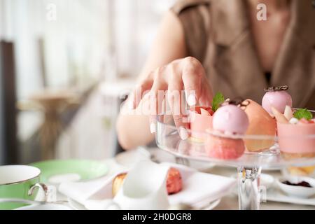 mano di donna asiatica che raccoglie un dessert da un piatto di vetro Foto Stock