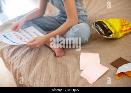 Un teen biondo, che segna i giorni dei suoi periodi in un calendario Foto Stock