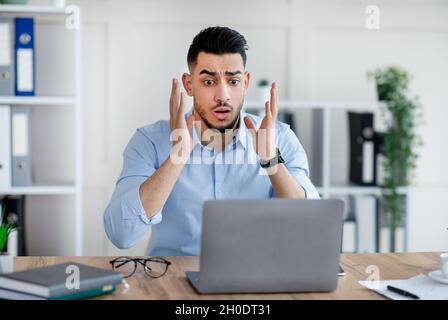 Ha sottolineato l'uomo d'affari arabo con laptop fare errore nel progetto di lavoro, non può rispettare la scadenza, si sente terrorizzato in ufficio Foto Stock