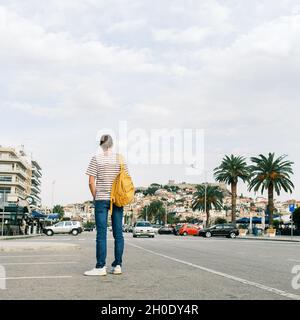 Giovane uomo con zaino che cammina sulla strada della città di Kavala, Grecia Foto Stock
