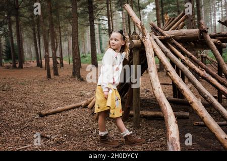 ragazza si è levata in piedi da casa di legno nella foresta in autunno Foto Stock