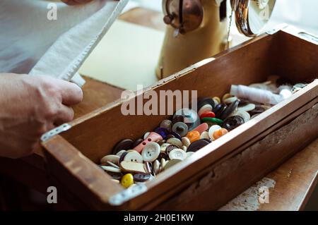 Scatola in legno vintage con bottoni retrò colorati su una macchina da cucire Foto Stock