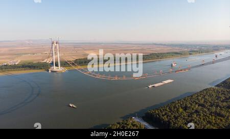 Vista panoramica aerea del drone dall'alto del ponte sospeso sul danubio, in costruzione, tra le città di Braila e Tulcea in Romania Foto Stock