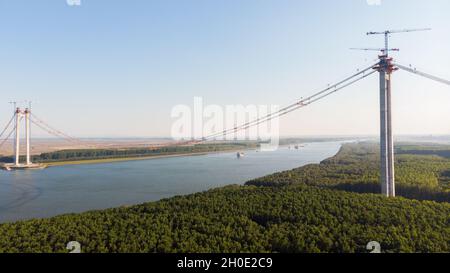 Vista panoramica aerea del drone dall'alto del ponte sospeso sul danubio, in costruzione, tra le città di Braila e Tulcea in Romania Foto Stock