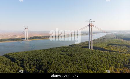 Vista panoramica aerea del drone dall'alto del ponte sospeso sul danubio, in costruzione, tra le città di Braila e Tulcea in Romania Foto Stock