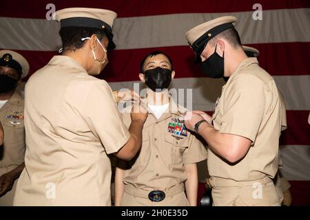 Il Chief Logistics Specialist di so, di Guyana, Sudamerica, assegnato al reparto di approvvigionamento di USS Gerald R. Ford (CVN 78), riceve i suoi ancoraggi durante la cerimonia di pinning del Chief Petty Officer di Ford tenuta nella baia di Hangar di Ford il 6 febbraio 2021. Ventitré marinai Ford furono fatti avanzare al rango di ufficiale principale di Petty. Foto Stock