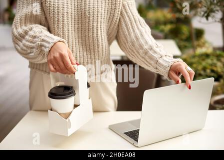primo piano donna mani tenere il caffè e laptop in città caffè terrazza Foto Stock