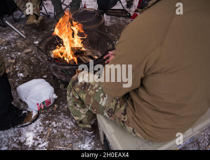 Colorado Air National Guard Airmen rilassarsi intorno a un fuoco tra l'allenamento durante Survival, Evasion, Resistance and Escape artic training nella San Isabel National Forest vicino Leadville, Colom., 9 febbraio 2021. La formazione si è concentrata sulla sopravvivenza a temperature inferiori allo zero utilizzando attrezzature a bordo della F-16 Fighting Falcon's Advanced Concept Ejection Seat II. Foto Stock