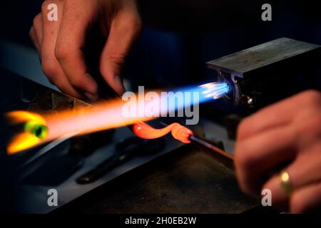 Le mani di un lavoratore di fiamma durante la fabbricazione di perle di vetro. Questa arte è stata iscritta nel 2020 sulla lista rappresentativa del patrimonio culturale immateriale Foto Stock