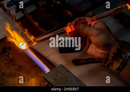 Le mani di un lavoratore di fiamma durante la fabbricazione di perle di vetro. Questa arte è stata iscritta nel 2020 sulla lista rappresentativa del patrimonio culturale immateriale Foto Stock