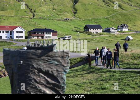 Gruppo di persone che passavano accanto alla scultura Merman a Elduvik, Isola Eysturoy, Isole Faroe, Scandinavia, Europa. Foto Stock