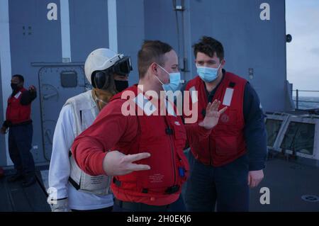 210213-N-CF707-1002 OCEANO PACIFICO (DAL 13, 2021) Hull Maintenance Technician 2nd Class Wane Debatin, middle, a native of Poconos, Ill., segnala a Damage Controlman 3rd Class Christopher Gers, right, a native of Lavergne, GA., durante un volo ponte crash drill a bordo di un incrociatore di classe Ticonderoga USS Lake Champlain (CG 57). Lake Champlain sta conducendo operazioni di routine nella terza flotta degli Stati Uniti area di attività. Foto Stock