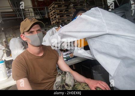 OKINAWA, Giappone (Feb 14, 2021) Information Systems Technician 2a classe Patrick Vowell, assegnato alla Naval Beach Unit 7, riceve una vaccinazione COVID-19 a bordo di una nave portuale di trasporto anfibio USS New Orleans (LPD 18). New Orleans, parte dell'America Expeditionary Strike Group, insieme alla 31st Marine Expeditionary Unit, sta operando nell'area di responsabilità della 7th Fleet statunitense per migliorare l'interoperabilità con alleati e partner e fungere da forza di risposta pronta per difendere la pace e la stabilità nella regione indopacifica. Foto Stock