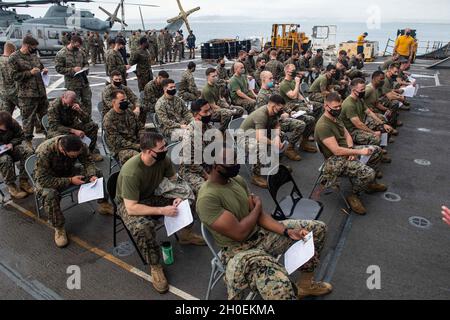 OKINAWA, Giappone (Feb 14, 2021) i Marines assegnati alla 31 Marine Expeditionary Unit aspettano di ricevere la loro vaccinazione COVID-19 a bordo della nave portuale di trasporto anfibio USS New Orleans (LPD 18). New Orleans, parte dell'America Expeditionary Strike Group, insieme al 31° MEU, opera nell'area di responsabilità della settima flotta statunitense per migliorare l'interoperabilità con alleati e partner e fungere da forza di reazione pronta a difendere la pace e la stabilità nella regione indopacifica. Foto Stock