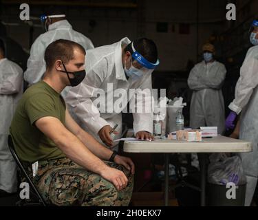 Una Marina degli Stati Uniti riceve la vaccinazione COVID-19 a bordo della USS New Orleans (LPD 18), a Okinawa, Giappone, 14 febbraio 2021. Il 31 MEU opera a bordo di navi dell'America Expeditionary Strike Group nella settima area di attività della flotta per migliorare l'interoperabilità con gli alleati e i partner e fungere da pronta forza di reazione per difendere la pace e la stabilità nella regione IndoPacifico. Foto Stock