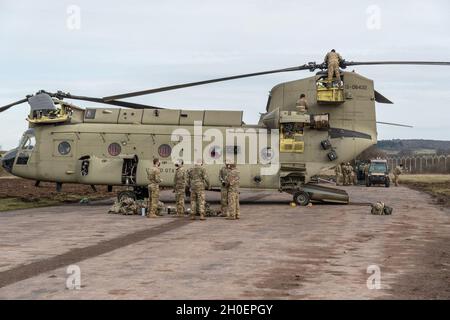 Soldati DELL'esercito DEGLI STATI UNITI assegnati al 1° Battaglione, 214 reggimento di aviazione, 12 ° brigata di aviazione di combattimento (12 ° CABINA), tirare la manutenzione e scaricare i loro CH-47 Chinook elicotteri, dopo l'arrivo al campo aereo dell'esercito degli Stati Uniti sulla manovra Training Area, Baumholder, Germania 16 febbraio 2021. Foto Stock