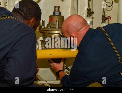 OCEANO INDIANO (dal 17, 2021) Gunner’s Mate 2nd Class Nicholas Mason, Left, e Aviation Ordnanceman 1st Class Matthew Watson preparano un tubo antincendio per iniziare il test e la manutenzione degli sprinkler a bordo della base del mare di Expeditionary USS Hershel “Woody” Williams (ESB 4) nell’Oceano Indiano, 17 febbraio 2021. Hershel Williams opera nella Sixth Fleet degli Stati Uniti per condurre una formazione sull'interoperabilità e creare partnership strategiche con i partner africani. Foto Stock