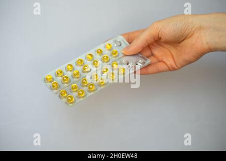 Piccolo complesso rotondo giallo di vitamine e minerali in una confezione blister in mano. Fuoco sulle pillole Foto Stock