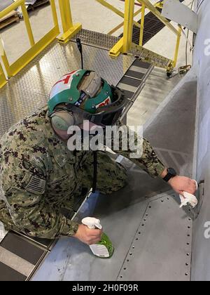 Navy Petty Officer di terza classe Kenneth Bondeson, un tecnico di elettronica per l'aviazione con la divisione Avionics del Naval Aviation Maintenance Center for Excellence, decontamina le aree ad alto traffico su un aereo F/A-18F Super Hornet con pulitore e disinfettante per l'aviazione pronto all'uso alla Naval Air Station Oceana, Virginia Beach, Virginia, 18 febbraio 2021. Il disinfettante spray è uno dei sette nuovi articoli del portafoglio di prodotti sostenibili della Defense Logistics Agency, ora disponibile presso DLA FedMall. Foto Stock