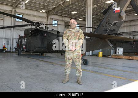 Christian Ernand, un pilota della Charlie Company, 2-149 Battaglione di supporto dell'Aviazione Generale, la Guardia Nazionale dell'Esercito del Texas riferisce alla risposta attiva dello stato al Winter Storm Uri Feb 19.2021, presso la struttura di supporto dell'Aviazione dell'Esercito di San Antonio, Martindale, Texas. Circa 32 soldati dell'unità hanno dichiarato di essere in servizio presso la struttura e hanno eseguito controlli di manutenzione e pianificazione pre-volo al fine di consegnare cibo e acqua alle comunità del Texas. Foto Stock