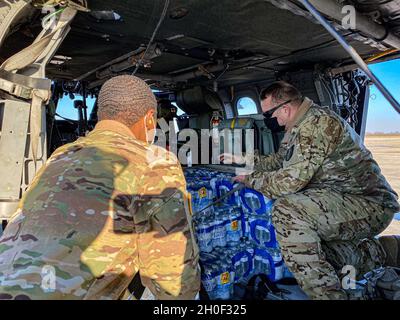 Soldiers of Charlie Company, 2-149th General Aviation Support Battaglione, Texas Army National Guard carica l'acqua in un UH-60 in risposta a Winter Storm Uri Feb 19.2021, presso il San Antonio Army Aviation Support Facility, Martindale, Texas. Circa 32 soldati dell'unità hanno dichiarato di essere in servizio presso la struttura e hanno eseguito controlli di manutenzione e pianificazione pre-volo al fine di consegnare cibo e acqua alle comunità del Texas. Foto Stock