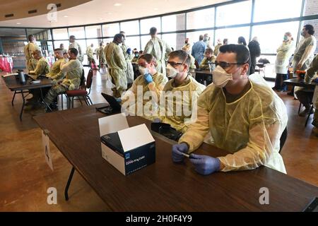 I soldati e gli Airmen della Guardia Nazionale del Nord Dakota si preparano a condurre test volontari BinaxNOW COVID-19 per i possessori di biglietti di calcio Bison della North Dakota state University nella lobby del Fargodome, Fargo, N.D., 21 febbraio 2021. Il servizio di test viene offerto ai partecipanti al gioco quando entrano nella struttura. Foto Stock