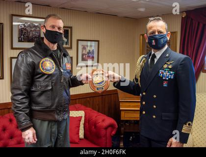 Gianfranco Vizzini, addetto navale, Right, presenta un regalo per conto del capitano della Marina italiana Giancarlo Ciappina, comandante del portaerei ITS Cavour (CVH 550), al capitano della Marina americana Cassidy Norman, comandante del portaerei USS John C. Stennis (CVN 74), Come parte di uno scambio di regali nella cabina di porto del capitano a bordo del John C. Stennis, a Norfolk, Virginia, 22 febbraio 2021. Il John C. Stennis collabora con Newport News Shipbuilding per completare la revisione del complesso di rifornimento in base ai tempi previsti con un equipaggio addestrato, resiliente e coeso. Foto Stock