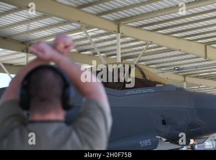 Senior Airman Zachary Lorenz, capo equipaggio della 63esima unità di manutenzione degli aeromobili, segnala il Major Nicholas “Jakal” Rallo, 63esimo pilota istruttore Fighter Squadron F-35A Lightning II, 22 febbraio 2021, presso la base militare Luke Air Force base, Arizona. Rallo è il primo pilota a Luke a completare 1,000 ore di volo nella F-35A. Questa pietra miliare mette in evidenza la capacità di Luke di formare e trasformare Airmen pronti per i combattimenti per soddisfare le esigenze di combattimento. Foto Stock