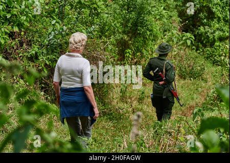Turista e Ranger camminando attraverso la foresta fino al lago Empakaai, Ngorongoro Conservation Area, Tanzania, Africa Foto Stock