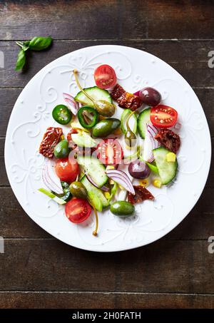 Insalata semplice con olive verdi e Kalamata, cetrioli, pomodori ciliegini e marinati, capperi e peperoni Jalapeno. Foto Stock