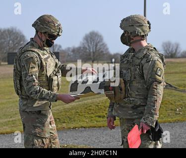 1° Sgt. Nicholas R. Bessent discutere i risultati del SPC. Anderson Target, entrambi con 1° Battaglione, 214° Regiment Aviazione, 12° Brigata Aviazione di combattimento, durante un esercizio di fuoco dal vivo in posizione inginocchiata con M4 Carbine, subito dopo il fuoco, con un caso espulso a mezz'aria. Baumholder Maneuvre Training Area, Range 21, Germania 24 febbraio 2021. Foto Stock