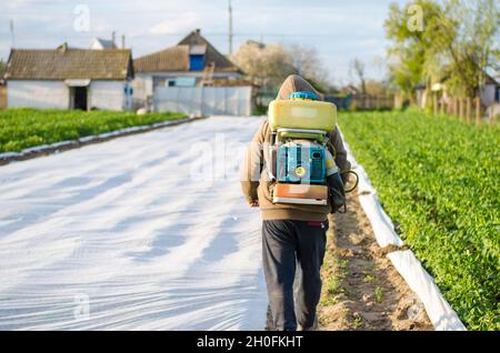 Oblast di Kherson, Ucraina - 4 maggio 2021: L'agricoltore spruzza una piantagione di patate con un irroratore. Nebulizzatore, fungicida e pesticida. Protezione del raccolto di cul Foto Stock