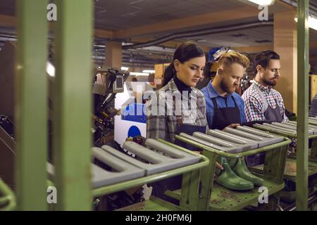 Gruppo di giovani lavoratori che lavorano in officina presso la fabbrica di calzature Foto Stock