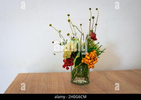 Ancora vita di arrangiamento fatto in casa di fiori e bacche su un tavolo. Decorazioni per la casa. Foto Stock