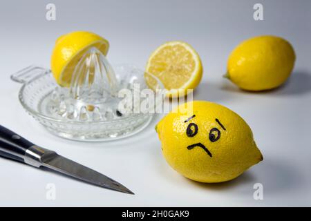 Limone infelice che guarda altri limoni tagliati e schiacciati Foto Stock