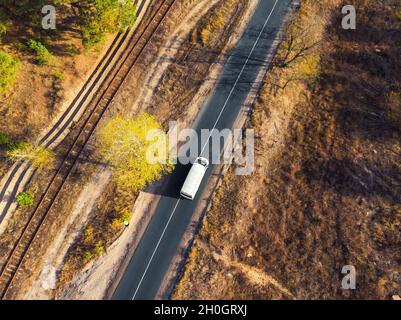 Aereo vista dall'alto bianco consegna moderna piccola spedizione cargo corriere van in movimento veloce su autostrada strada città urbano sobborgo. Distribuzione busines e. Foto Stock