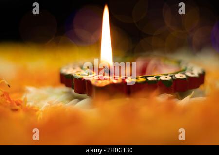 Fuoco selettivo - fiamme dritte affilate illuminanti da Clay Diya Deep dia con effetto Bokeh. Tema del Festival indiano per Diwali Pooja, Navratri, Duss Foto Stock