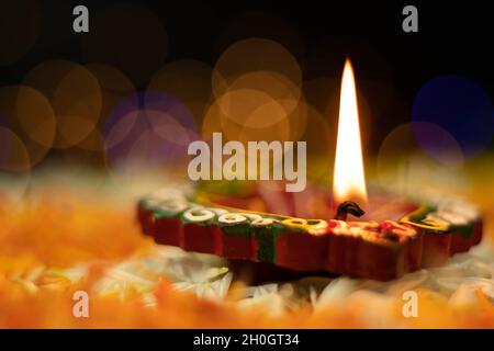 Fuoco selettivo - fiamme dritte affilate illuminanti da Clay Diya Deep dia con effetto Bokeh. Tema del Festival indiano per Diwali Pooja, Navratri, Duss Foto Stock