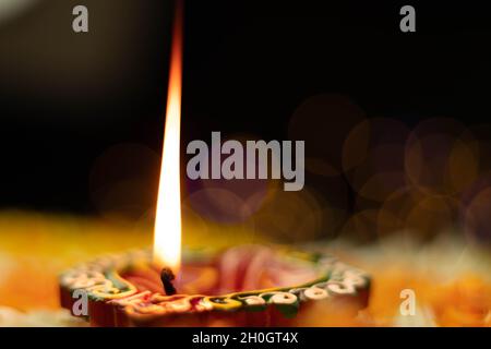 Fuoco selettivo - fiamme dritte affilate illuminanti da Clay Diya Deep dia con effetto Bokeh. Tema del Festival indiano per Diwali Pooja, Navratri, Duss Foto Stock