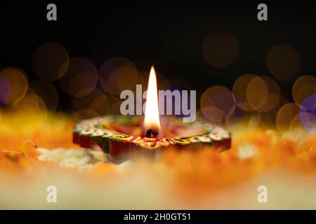 Fuoco selettivo - fiamme dritte affilate illuminanti da Clay Diya Deep dia con effetto Bokeh. Tema del Festival indiano per Diwali Pooja, Navratri, Duss Foto Stock