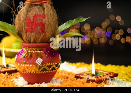 Fiamme dritte affilate che illuminano da Clay Diya Deep dia posto su Rangoli Fiore di Marigold con Kalash sul lato. Navratri Pooja, Dussehra Puja, N. Foto Stock