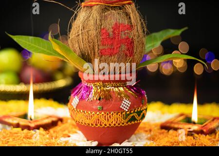 Terracotta Clay Kalash decorato con cocco, foglia di Mango posto su Rangoli Fiore Marigold con illuminazione Diya. Tema per Navratri Pooja, Dussehra Foto Stock