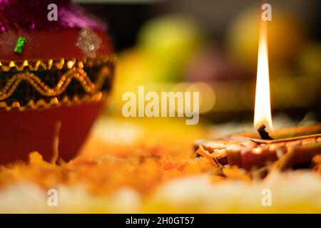 Fuoco selettivo - fiamme dritte affilate illuminanti da Clay Diya Deep dia con effetto Bokeh. Tema del Festival indiano per Diwali Pooja, Navratri, Duss Foto Stock