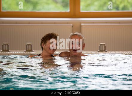 Le coppie anziane si divertono nella piscina coperta con acqua calda nel centro termale Foto Stock