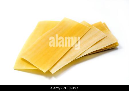 Lasagne crude non cotte isolate su sfondo bianco. Pila di fogli di pasta di lasagna secca non cotta Foto Stock